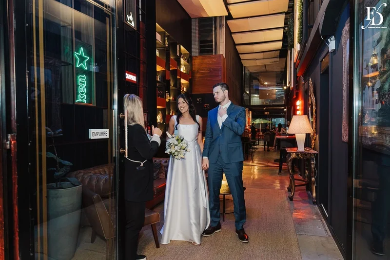 Casal Rafaella e Rafael sorrindo com buquê de lírios brancos após cerimônia de casamento