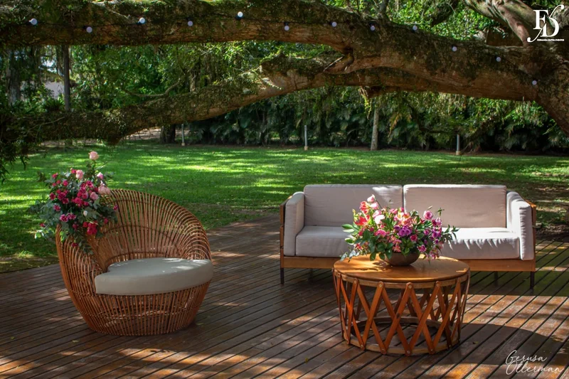 Lounge externo com sofá e varal de luzes sob a figueira.