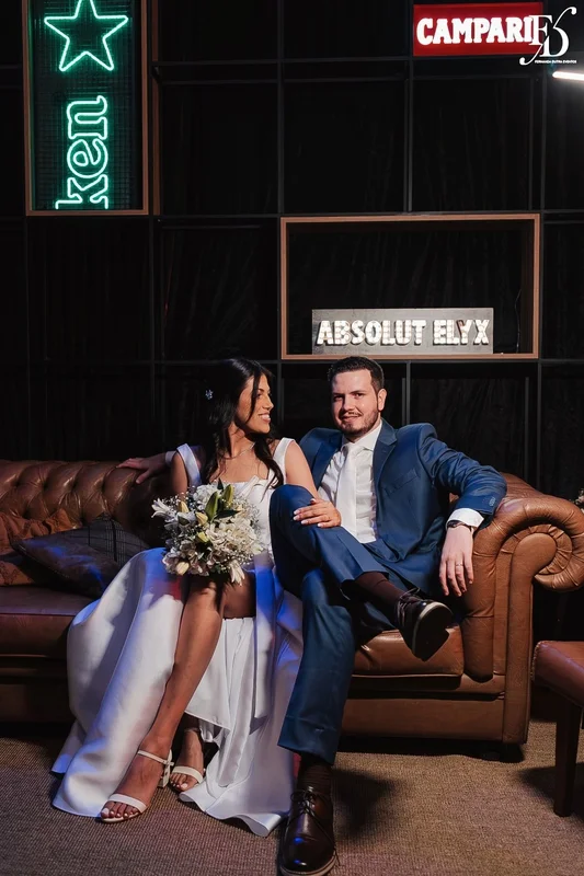 Casal Rafaella e Rafael sorrindo com buquê de lírios brancos após cerimônia de casamento