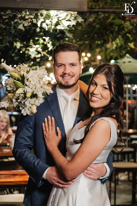 Casal Rafaella e Rafael sorrindo com buquê de lírios brancos após cerimônia de casamento