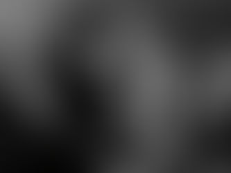 Woman in a sweater holds her head in her hand, sitting on a couch. The black-and-white image conveys a mood of stress or contemplation.