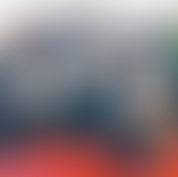 A group of 13 people holding certificates poses on steps in a room with a red carpet and wooden podium, creating a formal and celebratory mood.