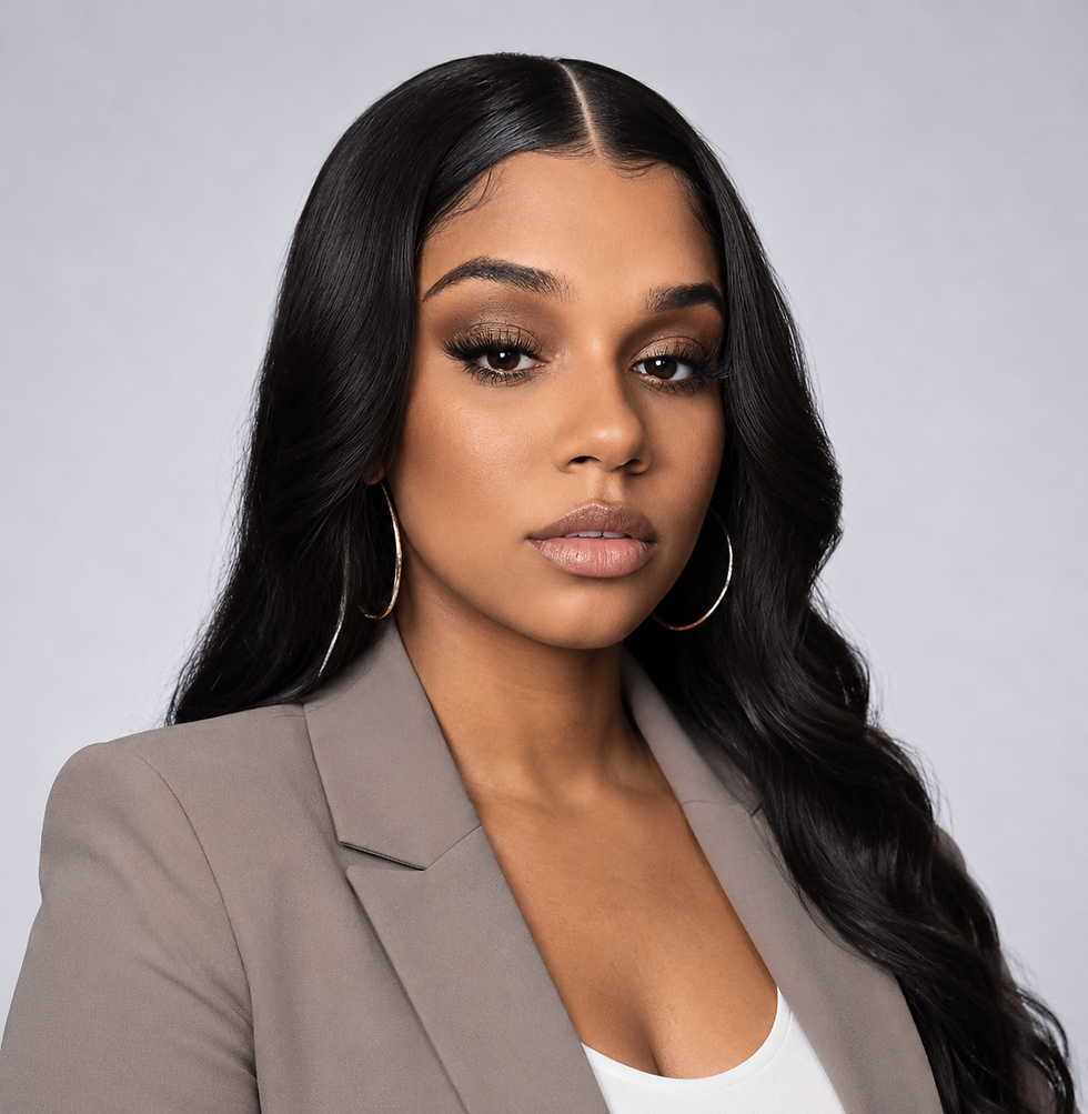 Portrait of a woman with long black hair, hoop earrings, and a gray blazer against a light gray backdrop, looking serious.