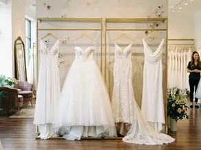 Luxury bridal boutique showroom with a diverse wedding dress silhouette mix on display racks.
