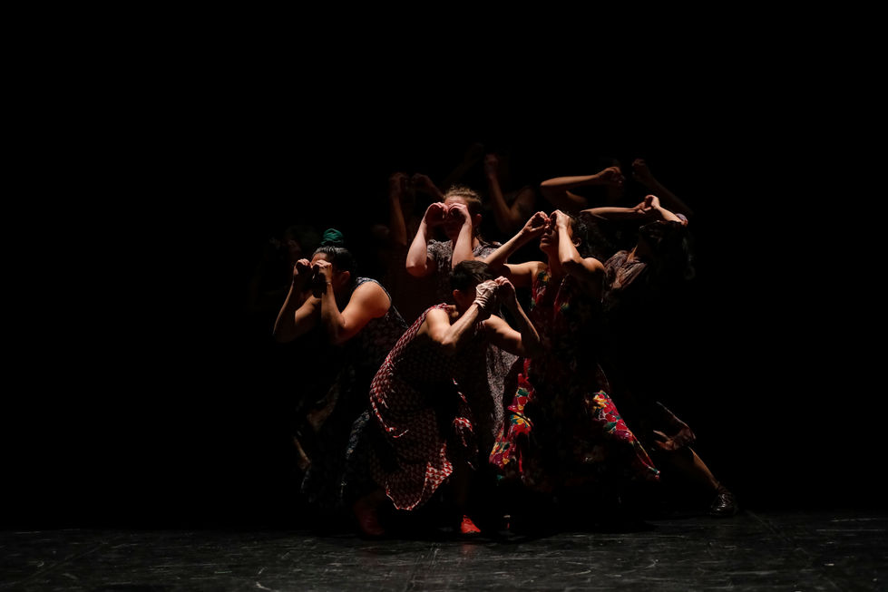 Un grupo de mujeres en penumbra hacen anteojos con sus manos Obra Gruta del Colectivo Beznei.