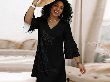 A woman wearing a loose black dress featuring a silhouette print of a cat. The sleeves are 3/4 length and ruffled.