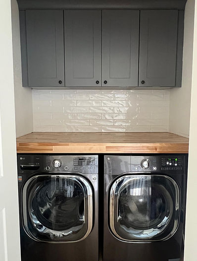 Efficient laundry space designed within a closet, featuring a washer and dryer, custom shelving, and smart storage so