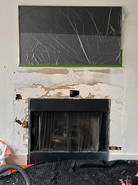 Beautifully renovated fireplace with a modern stone surround, custom mantel, and a cozy, inviting glow