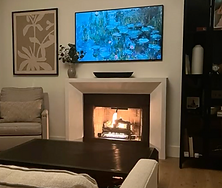 Beautifully renovated fireplace with a modern stone surround, custom mantel, and a cozy, inviting glow