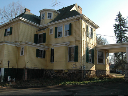 Yellow two-story home with dormer windows and a covered side porch.