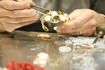 Italian artisan setting stones into a gold bracelet using jewelry tools with only the hands visible.