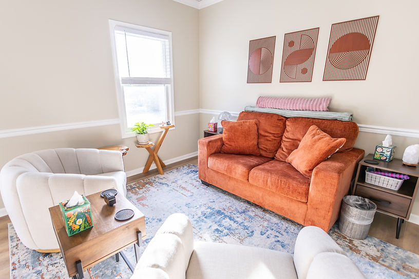 Cozy therapy room with orange sofa and white armchairs at Life's Journey Counseling in Louisville.