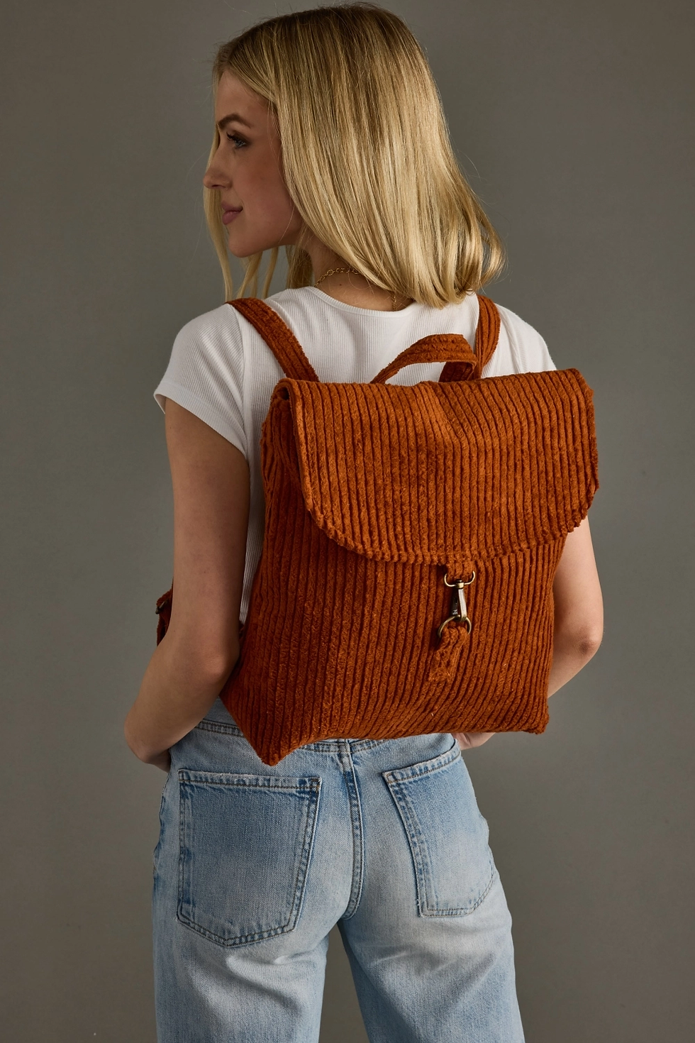 Rust Corduroy Backpack being worn by girl with a white shirt and blue jeans.
