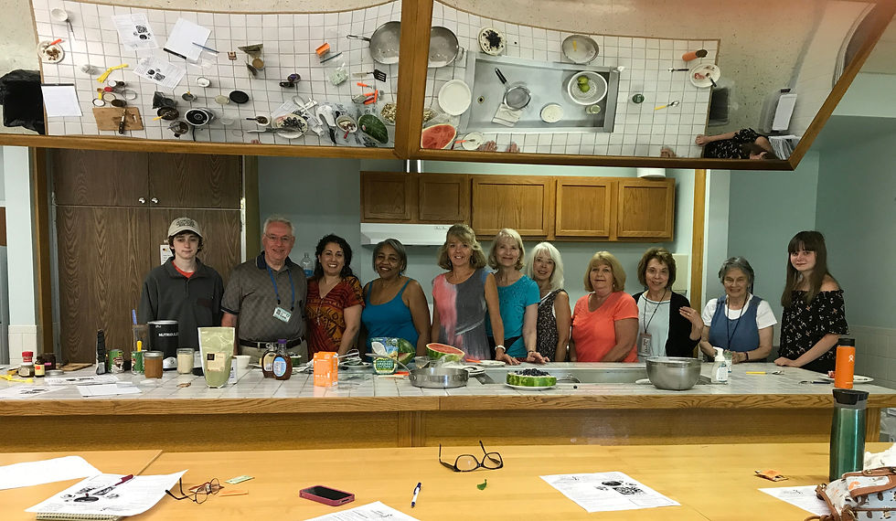 Large group of adults standing together in a kitchen during a cooking class.
