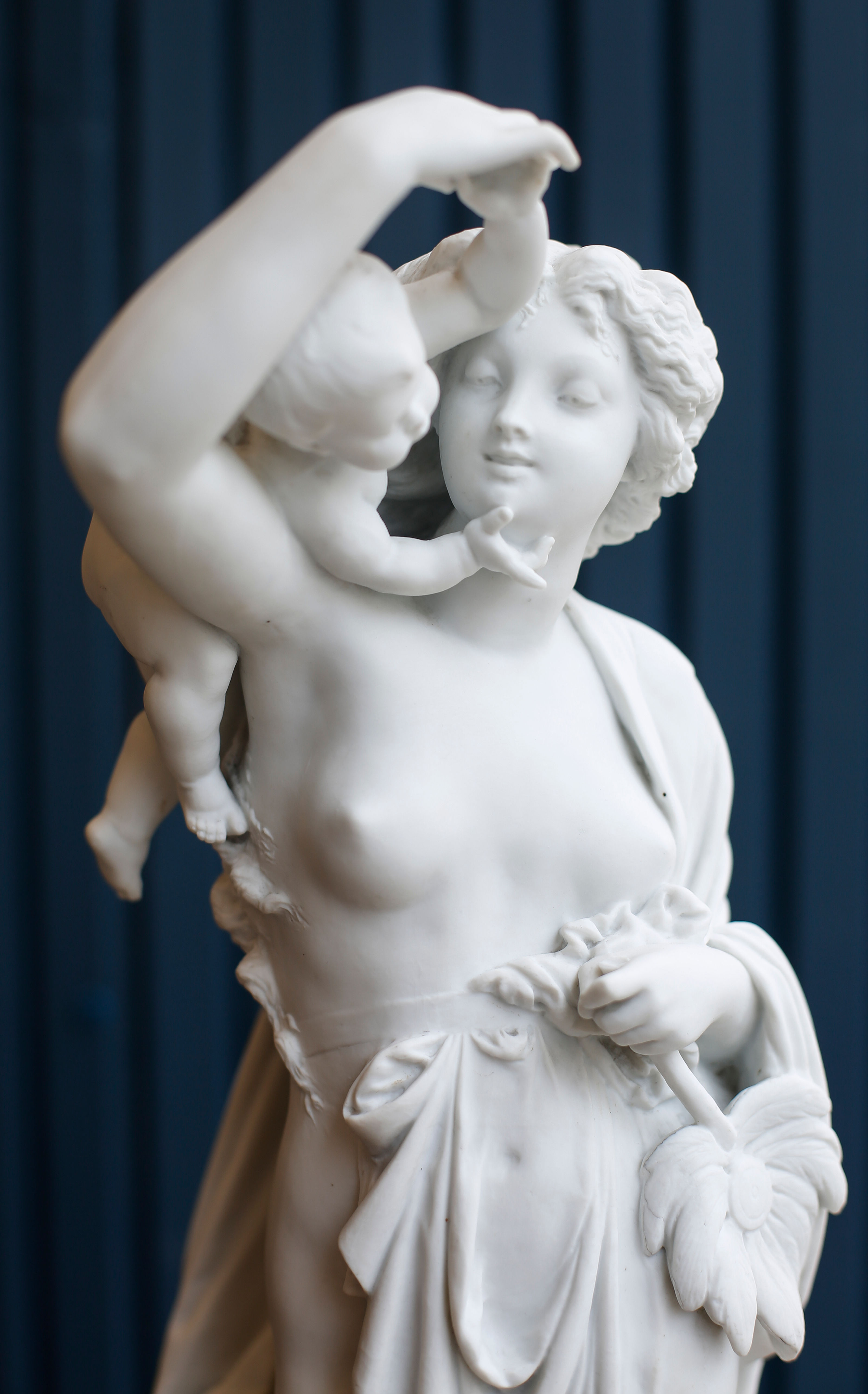 Pair of Large Figurines of Woman Contemplating a Child of Cupid