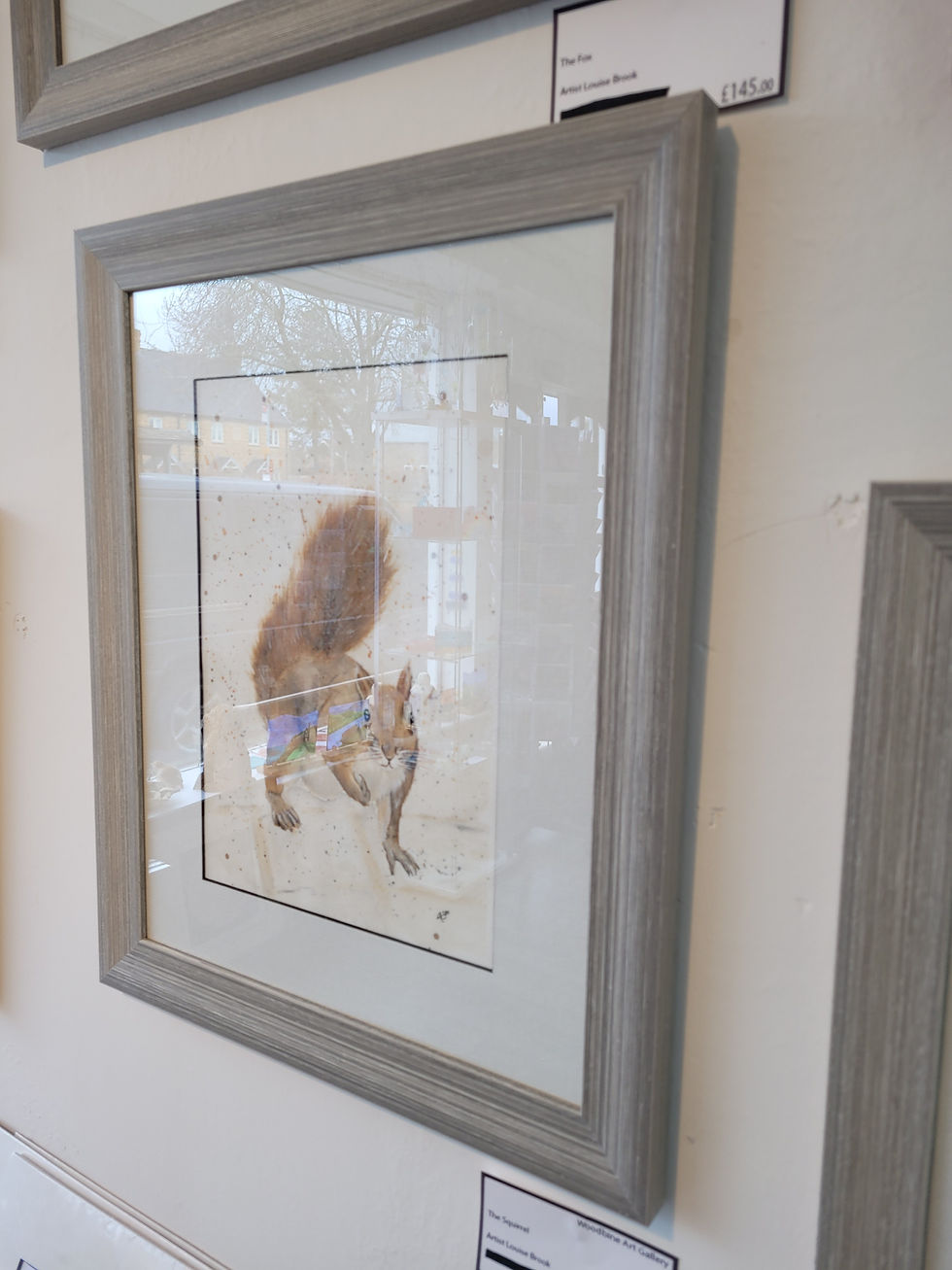 Thumbnail: Angle view (from RHS) of a framed red squirrel painting. Original watercolour depicting a red squirrel
