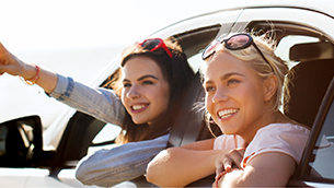 Two teenage females looking out open car windows.