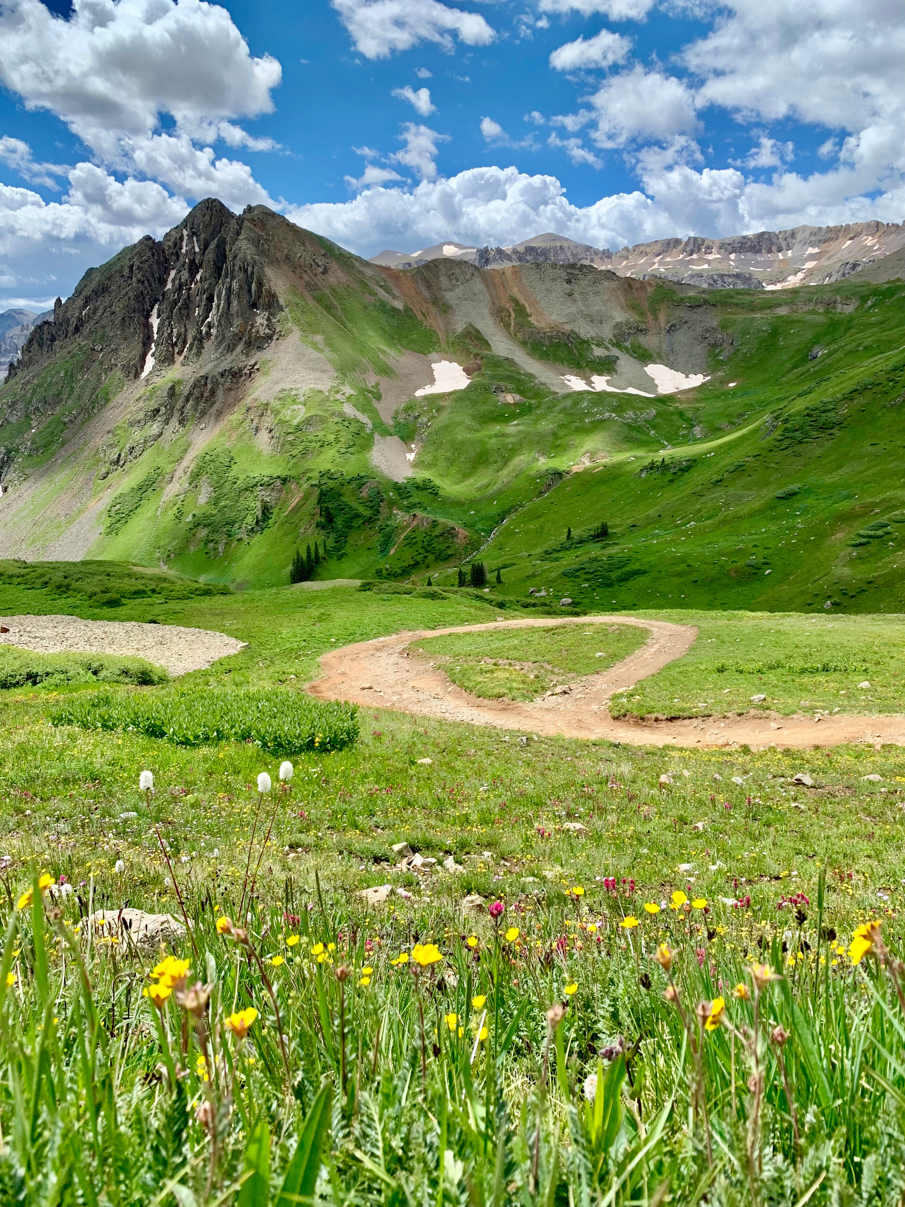 One Way In and One Way Out - circular dirt turnaround in a high green alpine basin beneath rugged peaks