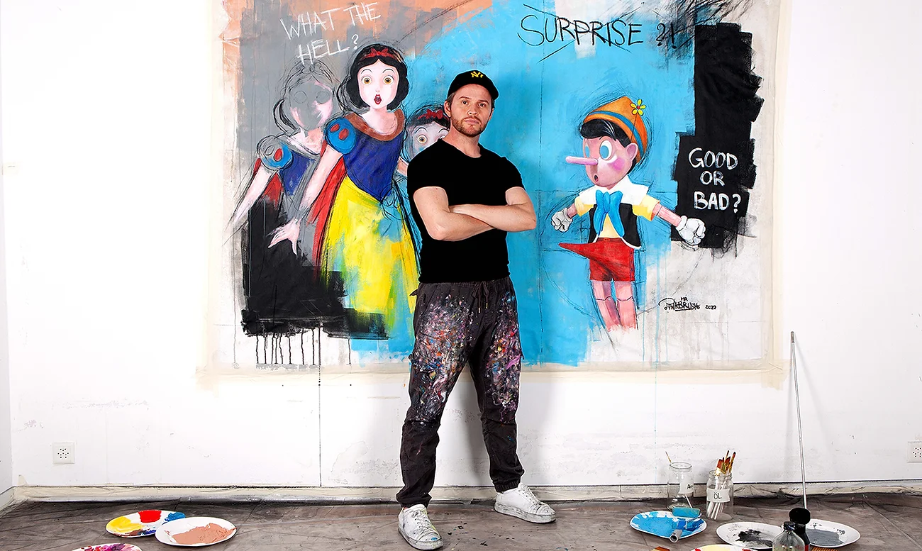 Contemporary Pop Artist Mr Pinkbrus standing in front of his original painting of Disney Snow White meeting Pinocchio