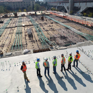 Photo depicts construction workers looking out over a construction site.