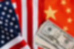 American currency on top of a U.S. and a China flag.