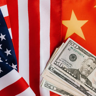 American currency on top of a U.S. and a China flag.