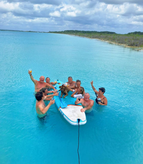 groupe de personne dans l'eau avec des verres sur un paddle. Un chien sur un paddle