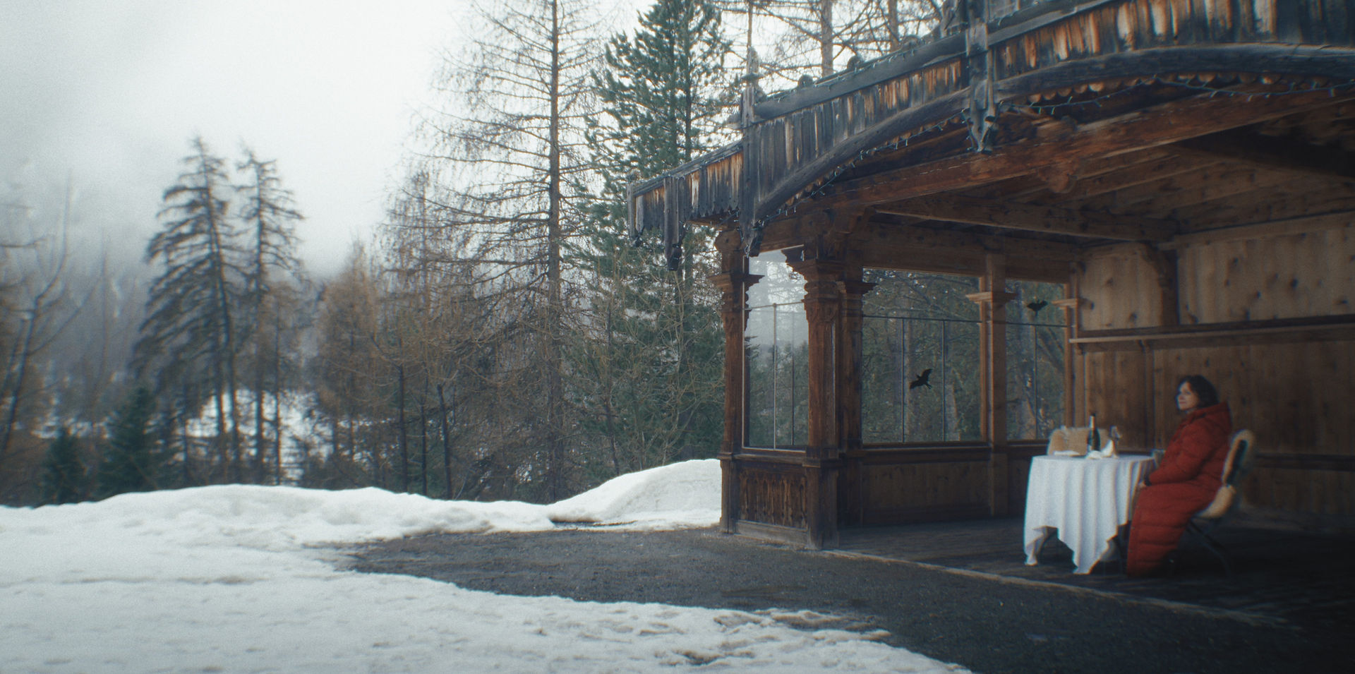 La véranda d'une maison dans la forêt. Le paysage est recouvert de neige.
