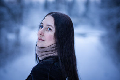 Woman in dark winter scarf, soft blue-grey tones, snowy landscape, Tromsø
Alt: Winter portrait woman dark scarf snowy landscape Tromsø Norway — cinematic photographer Andie Szatmari