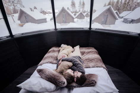 Couple asleep in glass dome cabin, snowy Arctic cabins visible above, Apukka Resort, Rovaniemi
Alt: Couple sleeping Arctic glass dome cabin Norway — intimate portrait photographer Andie Szatmari