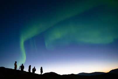 Group silhouetted on ridge under Northern Lights at dusk
Alt: Group silhouette ridge Northern Lights dusk Tromsø Norway — aurora borealis photographer Andie Szatmari