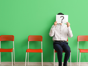 Candidate sitting on a chair, holding a paper with a question mark over their face, symbolizing uncertainty or confusion during the hiring process.