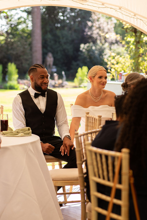 Bride and groom sat down in the wedding marquee holding hands.