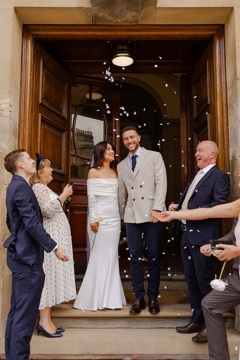 Newly weds walk out of Bath Guildhall as their guests throw confetti over them.