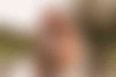 The groom holds the brides face as the look into each others eyes wit the river in the background.