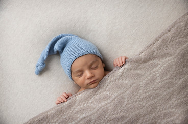 Nyfødt gutt med blå strikke lue. ole lukkeøye