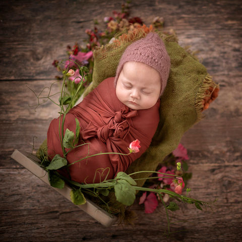 Nyfødt svøpt sovende i liten seng. dandert i hjemmedyrkede blomster, blomstereng