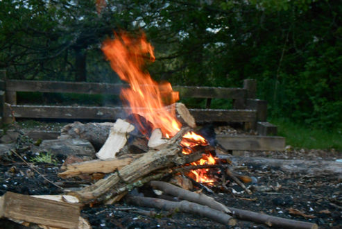 Photo of a campfire with the campfire circle benches in the background