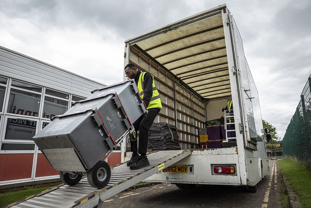 removal man pulling crates onto a van