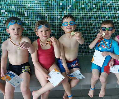 Vier kinderen met medailles en zwemdiploma's na een privézwemles van MultiFun in Geel.