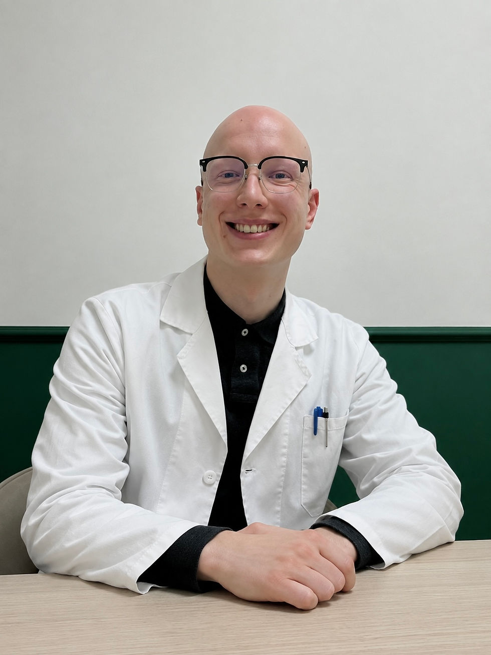 Dottore sorridente in camice bianco seduto alla scrivania