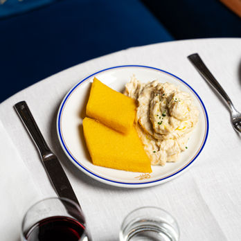 Cipriani’s creamy baccalà mantecato paired with golden polenta slices, artfully plated on fine white china with blue trim.