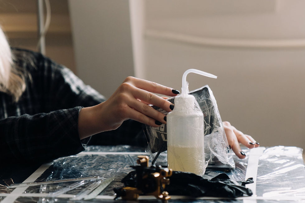 Gloved hands disinfecting a plastic-wrapped tattoo workstation