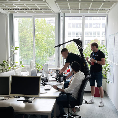 Filmcrew inszeniert eine Werbeszene in einem hellen, modernen Büro mit Schauspielern.