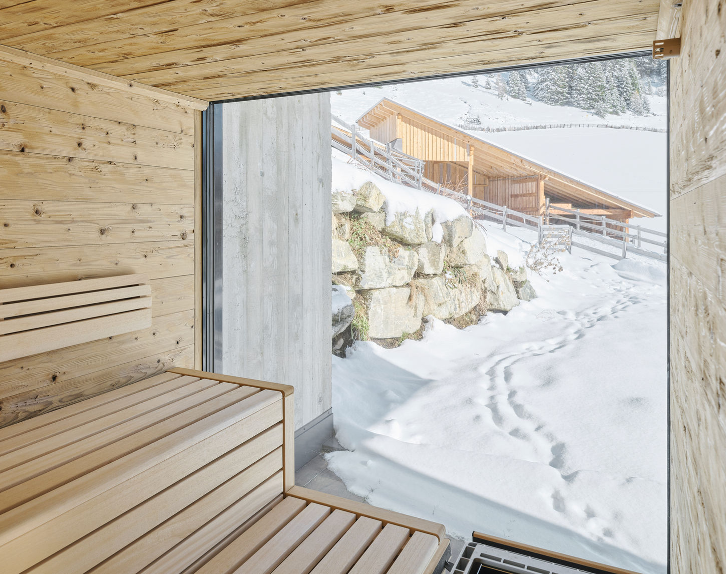 In einem kleinen Weiler der Tiroler Gemeinde Haiming, umgeben von ländlicher Idylle, erhebt sich ein neues Wohnhaus das nicht nur die Vergangenheit respektiert, sondern auch die Zukunft gestaltet. Sensibel fügt sich das neue Gebäude in die bestehende Umgebung ein und überrascht mit seiner differenzierten Baukörperplastik, die bei genauer Betrachtung eine faszinierende Geschichte erzählt. Bereits bei der Zufahrt zum Gebäude wird der Besucher von einer harmonischen Symbiose aus Vergangenheit und Gegenwart begrüßt. Das Eingangsgebäude mit Satteldach und brauner Holzfassade auf Straßenniveau zollen dem gegenüberliegenden Bauernhaus Tribut. Über dieses gelangt man in den Wohnbereich welcher sich durch eine raumhohe Verglasung öffnet und einen Panoramablick auf die naturbelassene Umgebung bietet. Unterhalb der dieses Wohnbereiches finden die Pferde der hauseigenen Zucht ihr neues Zuhause. Die Betonfassade mit Bretterschalung verleiht dem unteren Teil des Gebäudes eine zeitgemäße Ästhetik, die sich wohltuend von der traditionellen Umgebung abhebt. Im Inneren kontrastieren die klaren Sichtbetonwände mit heimischen Eichenholz und naturbelassenen Stahl. Wohnhaus LFD | Marlstein | ROECK Architekten | Innsbruck | Haus modern | Architekt Innsbruck | Sichtbeton | Wohnhaus Tirol | Stallgebäude | Pferdezucht | ROECK Architekten | Röck | Karlheinz Röck | Architekturbüro Röck