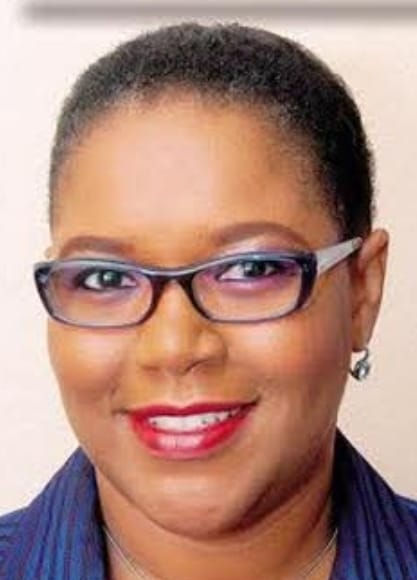 Professional headshot of Marline Stephenson-Dalley wearing glasses and red lipstick, dressed in a blue outfit. 