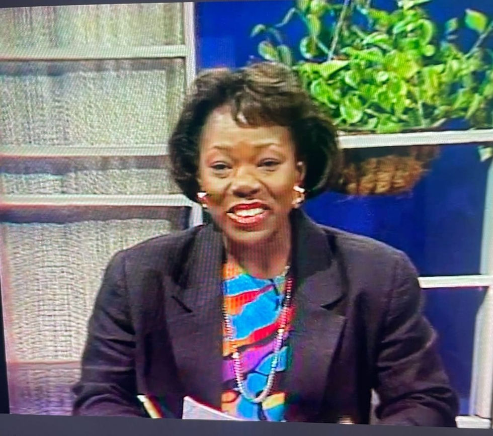 A smiling Darcy Tulloch, dressed in a colourful blouse and a dark blazer, on the set of Morning Time.