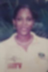 A smiling Dahlia Harris in a cream T-shirt with palm leaves in the background.