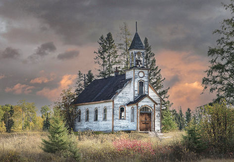 Weathered hilltop community church silhouetted against a colourful sunset sky, warm orange and pink hues glowing behind it.
