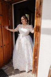 Braut in weißem Hochzeitsdirndl mit Spitzenärmeln
